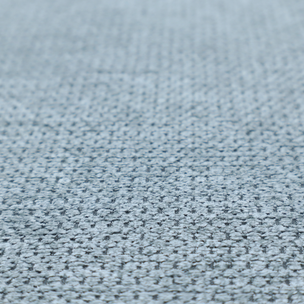 A textured fabric in a light steel or airy powder blue. This material features a dense, rhythmic weave with a tactile, honeycomb-like surface. The colour is a cool, soft frost blue, achieved by interlacing pale blue threads with darker grey base fibres, resulting in a weathered, multidimensional look that feels light yet substantial.
