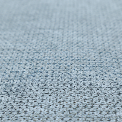 A textured fabric in a light steel or airy powder blue. This material features a dense, rhythmic weave with a tactile, honeycomb-like surface. The colour is a cool, soft frost blue, achieved by interlacing pale blue threads with darker grey base fibres, resulting in a weathered, multidimensional look that feels light yet substantial.