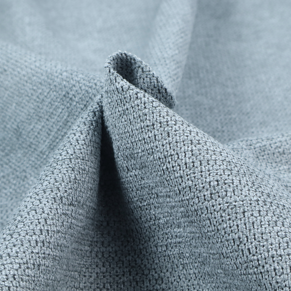 A textured fabric in a light steel or airy powder blue. This material features a dense, rhythmic weave with a tactile, honeycomb-like surface. The colour is a cool, soft frost blue, achieved by interlacing pale blue threads with darker grey base fibres, resulting in a weathered, multidimensional look that feels light yet substantial.