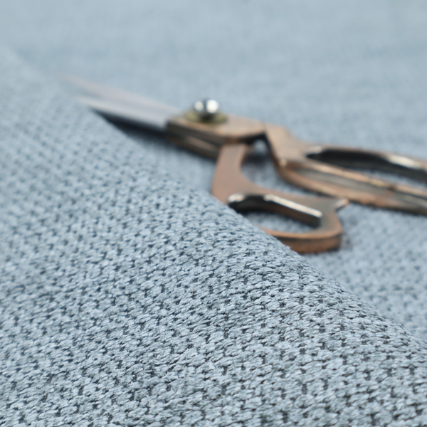 A textured fabric in a light steel or airy powder blue. This material features a dense, rhythmic weave with a tactile, honeycomb-like surface. The colour is a cool, soft frost blue, achieved by interlacing pale blue threads with darker grey base fibres, resulting in a weathered, multidimensional look that feels light yet substantial.