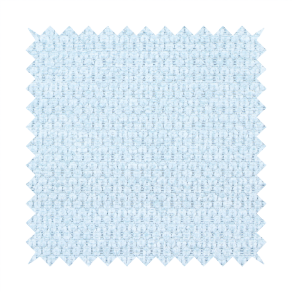 A textured fabric in a pale sky blue. This material features a dense, rhythmic weave with a delicate honeycomb-like surface. The colour is a bright, airy pastel blue, achieved by interlacing soft blue threads with a crisp white base, resulting in a luminous, clean appearance that emphasizes the fabric's tactile grid.