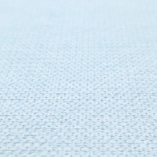 A textured fabric in a pale sky blue. This material features a dense, rhythmic weave with a delicate honeycomb-like surface. The colour is a bright, airy pastel blue, achieved by interlacing soft blue threads with a crisp white base, resulting in a luminous, clean appearance that emphasizes the fabric's tactile grid.