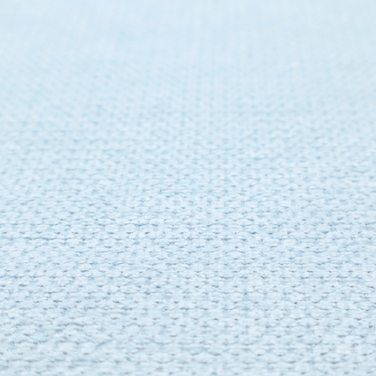 A textured fabric in a pale sky blue. This material features a dense, rhythmic weave with a delicate honeycomb-like surface. The colour is a bright, airy pastel blue, achieved by interlacing soft blue threads with a crisp white base, resulting in a luminous, clean appearance that emphasizes the fabric's tactile grid.