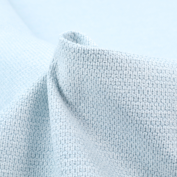A textured fabric in a pale sky blue. This material features a dense, rhythmic weave with a delicate honeycomb-like surface. The colour is a bright, airy pastel blue, achieved by interlacing soft blue threads with a crisp white base, resulting in a luminous, clean appearance that emphasizes the fabric's tactile grid.