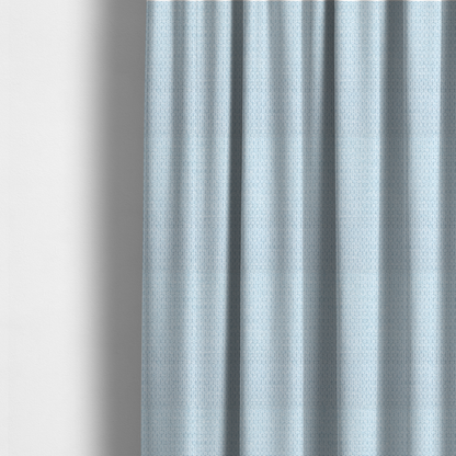 The fabric used to create these made-to-measure curtains is a textured fabric in a pale sky blue. This material features a dense, rhythmic weave with a delicate honeycomb-like surface. The colour is a bright, airy pastel blue, achieved by interlacing soft blue threads with a crisp white base, resulting in a luminous, clean appearance that emphasizes the fabric's tactile grid.