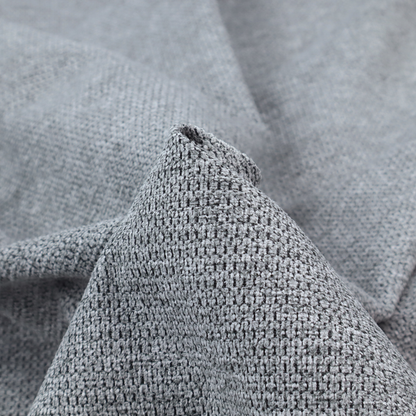 A textured fabric in a classic charcoal or weathered grey. The material features a dense, rhythmic weave with a tactile, pebbled surface. The colour is a sophisticated mid-grey, achieved by interlacing silver-grey threads with darker black base fibres, creating a high-contrast, multidimensional look that feels balanced and durable.