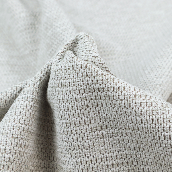 A textured fabric in light greige or pale oatmeal. The material features a dense, rhythmic honeycomb weave. The colour is achieved by interlacing light cream threads with cool grey base fibres, creating a neutral, stony appearance with a soft, pebbled tactile surface.