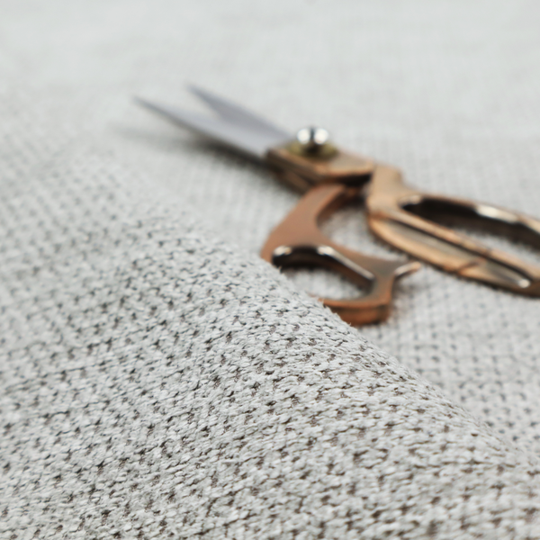 A textured fabric in a soft dove grey. This swatch features the signature uniform honeycomb weave, but with a lighter, more silver-toned profile than the previous neutral. The interlacing of white and light grey threads gives it a crisp, clean, and airy aesthetic.