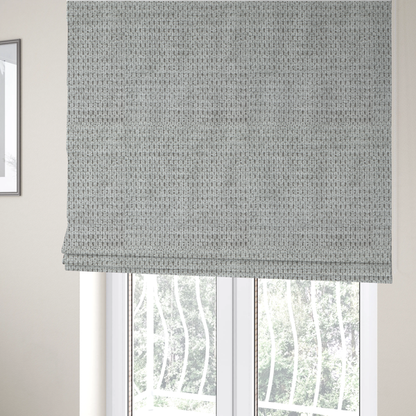 The fabric used to create these Roman blinds is a textured fabric in a soft dove grey. This swatch features the signature uniform honeycomb weave, but with a lighter, more silver-toned profile than the previous neutral. The interlacing of white and light grey threads gives it a crisp, clean, and airy aesthetic.