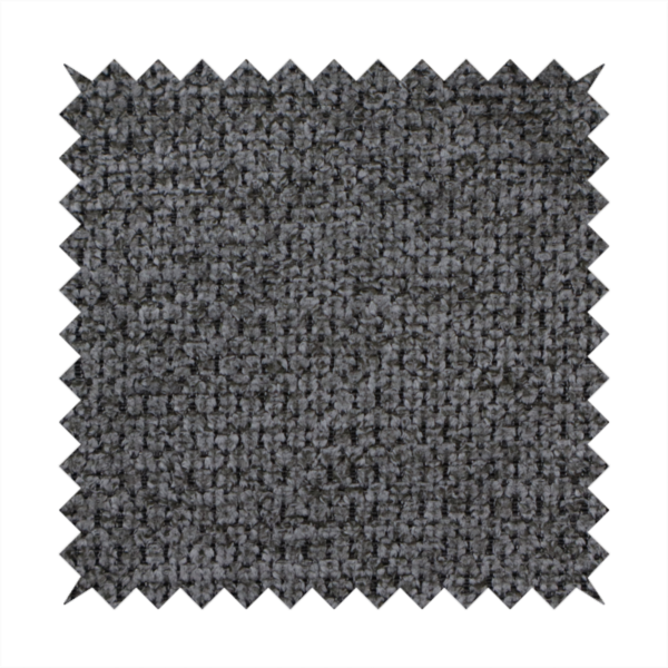 A textured fabric in a deep charcoal or soft black tone. This swatch features the signature rhythmic honeycomb weave of the collection. The colour is a rich, dark obsidian, achieved by tightly interlacing black threads with very subtle dark grey highlights, creating a moody, high-relief surface that absorbs and reflects light in a sophisticated, matte-metallic way.