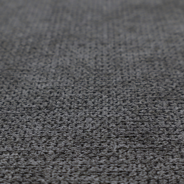A textured fabric in a deep charcoal or soft black tone. This swatch features the signature rhythmic honeycomb weave of the collection. The colour is a rich, dark obsidian, achieved by tightly interlacing black threads with very subtle dark grey highlights, creating a moody, high-relief surface that absorbs and reflects light in a sophisticated, matte-metallic way.