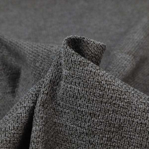 A textured fabric in a deep charcoal or soft black tone. This swatch features the signature rhythmic honeycomb weave of the collection. The colour is a rich, dark obsidian, achieved by tightly interlacing black threads with very subtle dark grey highlights, creating a moody, high-relief surface that absorbs and reflects light in a sophisticated, matte-metallic way.