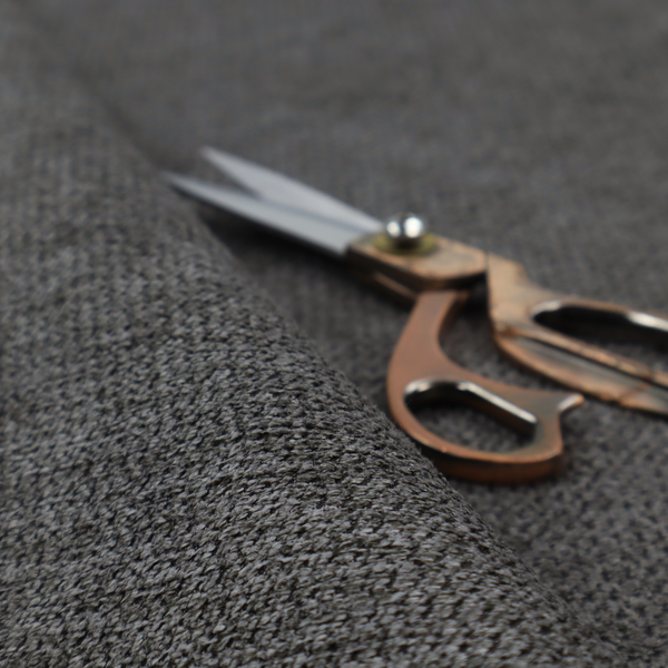 A textured fabric in a deep charcoal or soft black tone. This swatch features the signature rhythmic honeycomb weave of the collection. The colour is a rich, dark obsidian, achieved by tightly interlacing black threads with very subtle dark grey highlights, creating a moody, high-relief surface that absorbs and reflects light in a sophisticated, matte-metallic way.