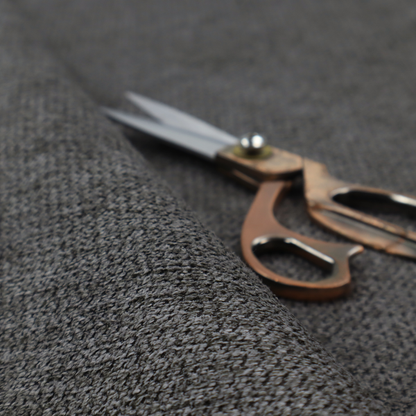 A textured fabric in a deep charcoal or soft black tone. This swatch features the signature rhythmic honeycomb weave of the collection. The colour is a rich, dark obsidian, achieved by tightly interlacing black threads with very subtle dark grey highlights, creating a moody, high-relief surface that absorbs and reflects light in a sophisticated, matte-metallic way.