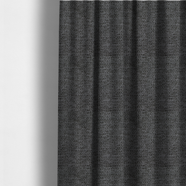 The fabric used to create these made-to-measure curtains is a textured fabric in a deep charcoal or soft black tone. This swatch features the signature rhythmic honeycomb weave of the collection. The colour is a rich, dark obsidian, achieved by tightly interlacing black threads with very subtle dark grey highlights, creating a moody, high-relief surface that absorbs and reflects light in a sophisticated, matte-metallic way.