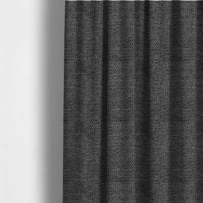 The fabric used to create these made-to-measure curtains is a textured fabric in a deep charcoal or soft black tone. This swatch features the signature rhythmic honeycomb weave of the collection. The colour is a rich, dark obsidian, achieved by tightly interlacing black threads with very subtle dark grey highlights, creating a moody, high-relief surface that absorbs and reflects light in a sophisticated, matte-metallic way.