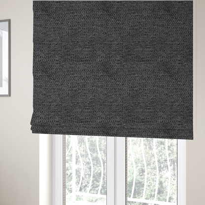 The fabric used to create these Roman blinds is a textured fabric in a deep charcoal or soft black tone. This swatch features the signature rhythmic honeycomb weave of the collection. The colour is a rich, dark obsidian, achieved by tightly interlacing black threads with very subtle dark grey highlights, creating a moody, high-relief surface that absorbs and reflects light in a sophisticated, matte-metallic way.