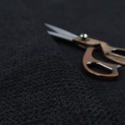 A textured fabric in midnight black. This swatch represents the deepest tone in the collection, featuring a uniform, tight waffle-weave. The monochromatic black threads create a subtle play of shadow within the geometric grid, offering a sleek, architectural aesthetic.