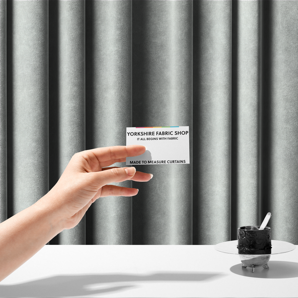 The fabric used to create these made-to-measure curtains is a pale off-white or cream-colored fabric featuring a fine, subtle grid-like texture. The weave consists of horizontal and vertical threads that create a soft, matte finish with a minimalist, clean aesthetic.