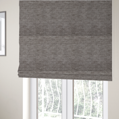 The fabric used to create these Roman blinds is a taupe or ash brown fabric with a dense, horizontal ribbed texture. The material features a soft, velvety pile that creates subtle light-catching highlights and shadows across the linear weave.