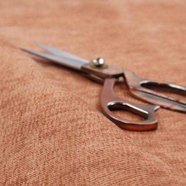 A burnt orange fabric with a dense, horizontal corded texture. The weave has a soft, plush pile similar to corduroy, creating a rich tonal depth with warm highlights and subtle shadows across the linear pattern.