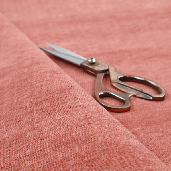 A dusty rose or salmon-pink fabric with a soft, multi-directional texture. While it maintains a subtle horizontal grain, the weave is more flecked and feathered than previous styles, creating a plush, velvet-like surface with organic light-catching highlights.