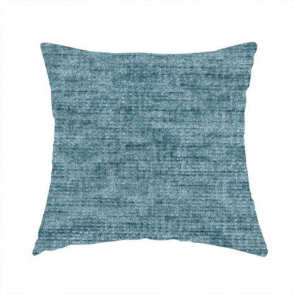 The fabric used to create this handmade cushion is a teal or dusty blue fabric with a soft, weathered texture. The weave features a subtle horizontal grain with a plush, multi-tonal pile that blends shades of slate and ocean blue for a rich, tactile appearance.