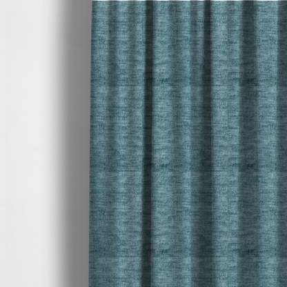 The fabric used to create these made-to-measure curtains is a teal or dusty blue fabric with a soft, weathered texture. The weave features a subtle horizontal grain with a plush, multi-tonal pile that blends shades of slate and ocean blue for a rich, tactile appearance.