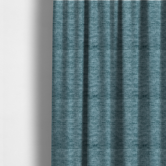 The fabric used to create these made-to-measure curtains is a teal or dusty blue fabric with a soft, weathered texture. The weave features a subtle horizontal grain with a plush, multi-tonal pile that blends shades of slate and ocean blue for a rich, tactile appearance.