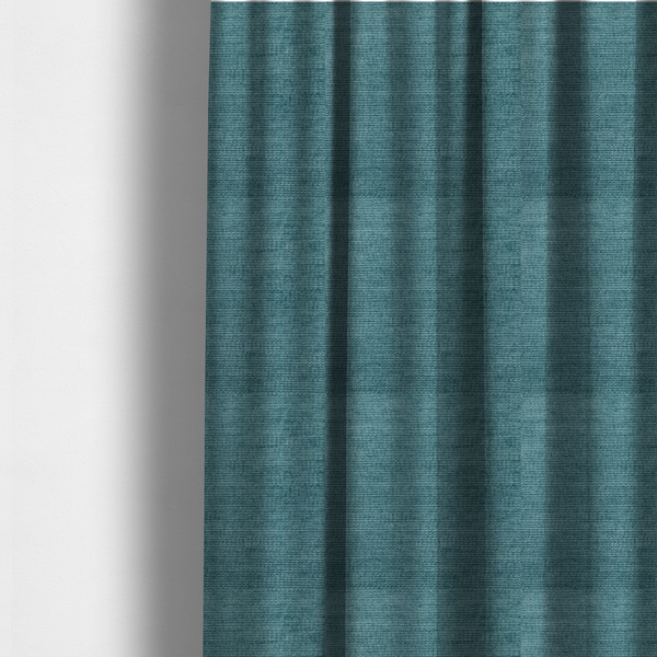 The fabric used to create these made-to-measure curtains is a deep peacock blue fabric with a structured horizontal corded texture. The plush, velvety ridges create a dense linear pattern, offering a sophisticated play of light and shadow with a soft, durable finish.