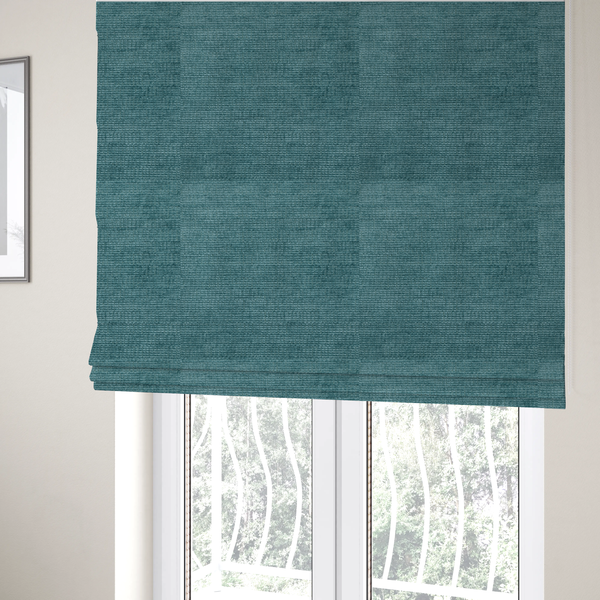 The fabric used to create these Roman blinds is a deep peacock blue fabric with a structured horizontal corded texture. The plush, velvety ridges create a dense linear pattern, offering a sophisticated play of light and shadow with a soft, durable finish.