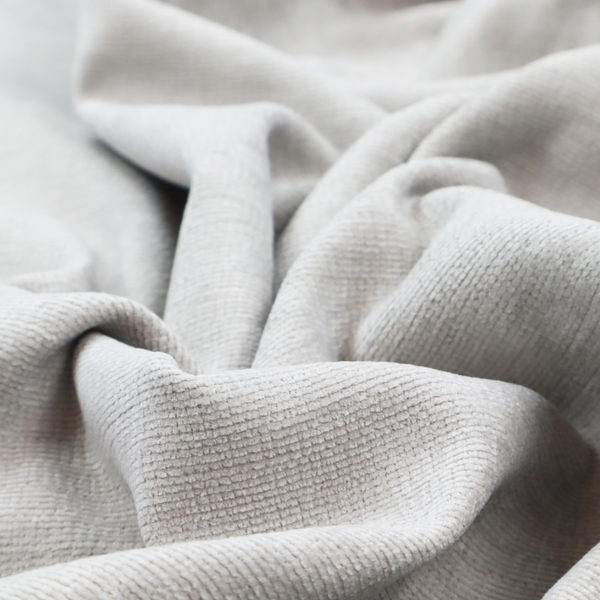 A light grey fabric with a soft, uniform horizontal ribbed texture. The weave has a plush, velvety pile that creates subtle shadows and highlights across the linear ridges, providing a clean, modern aesthetic with a tactile feel.