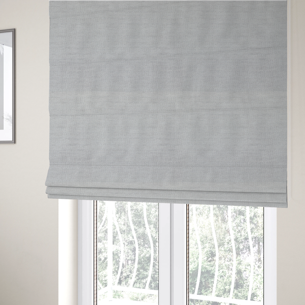 The fabric used to create these Roman blinds is a light grey fabric with a soft, uniform horizontal ribbed texture. The weave has a plush, velvety pile that creates subtle shadows and highlights across the linear ridges, providing a clean, modern aesthetic with a tactile feel.