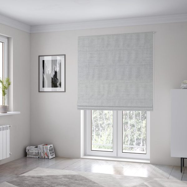 The fabric used to create these Roman blinds is a light grey fabric with a soft, uniform horizontal ribbed texture. The weave has a plush, velvety pile that creates subtle shadows and highlights across the linear ridges, providing a clean, modern aesthetic with a tactile feel.