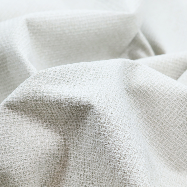 A light-coloured, woven contract fabric. The material features a fine, grid-like texture resembling a mix of linen and grass cloth in a neutral off-white or pale pearl tone. The weave creates a subtle, matte geometric pattern with delicate shadows that give the surface a tactile, three-dimensional appearance.