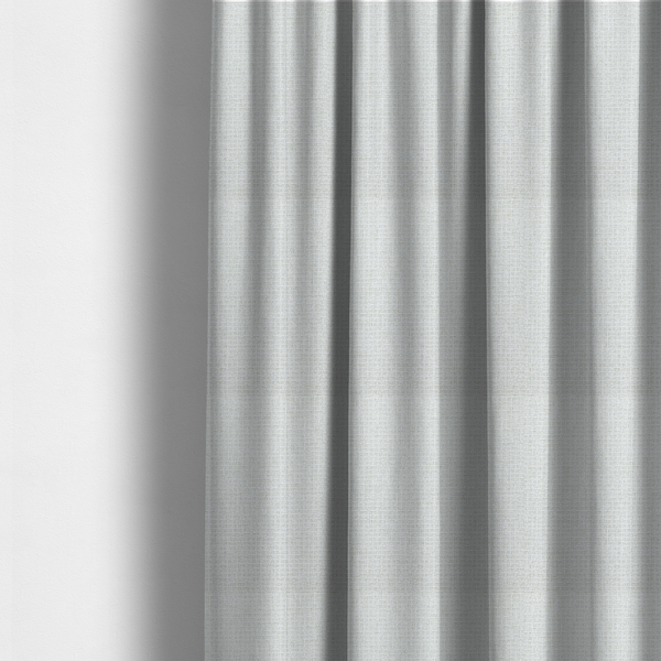 The fabric used to create these made-to-measure curtains is a light-coloured, woven contract fabric. The material features a fine, grid-like texture resembling a mix of linen and grass cloth in a neutral off-white or pale pearl tone. The weave creates a subtle, matte geometric pattern with delicate shadows that give the surface a tactile, three-dimensional appearance.
