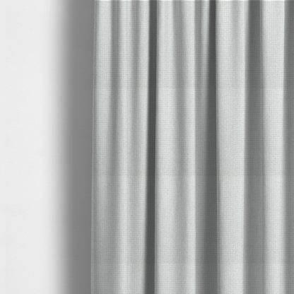 The fabric used to create these made-to-measure curtains is a light-coloured, woven contract fabric. The material features a fine, grid-like texture resembling a mix of linen and grass cloth in a neutral off-white or pale pearl tone. The weave creates a subtle, matte geometric pattern with delicate shadows that give the surface a tactile, three-dimensional appearance.