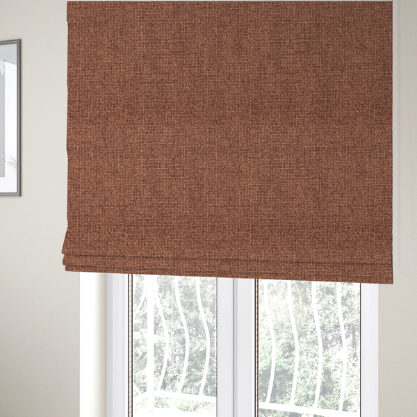 The fabric used to create these Roman blinds is a upholstery fabric in a warm terracotta or burnt orange shade. The textile features a multi-tonal basket weave with interlacing copper and dark brown threads, creating a rich, textured linen-look surface with an earthy, matte finish.