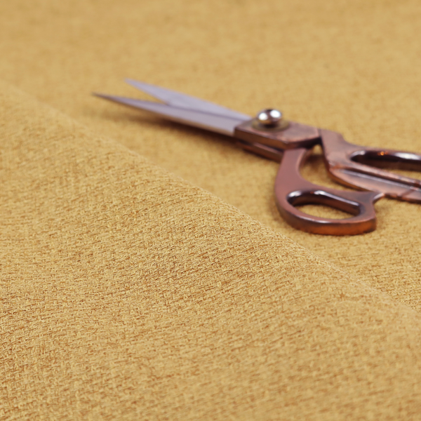 An upholstery fabric in a bright mustard or golden ochre shade. The textile features a dense, multi-tonal basket weave with interlacing threads of yellow, gold, and light tan, creating a vibrant, linen-look texture with a matte finish.