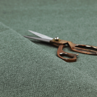 An upholstery fabric in a serene seafoam or muted teal shade. The textile features a dense, multi-tonal weave with interlacing threads of dusty blue-green and dark charcoal, creating a textured, linen-look surface with a matte finish.