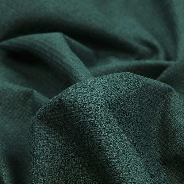 An upholstery fabric in a deep forest or emerald green shade. The textile features a dense, multi-tonal weave with interlaced threads of dark teal and charcoal, creating a rich, textured linen-look surface with a sophisticated matte finish.