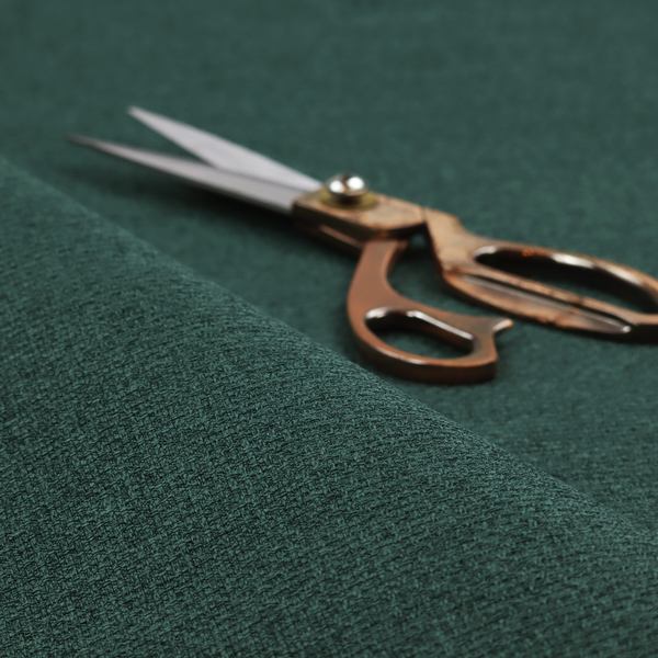 An upholstery fabric in a deep forest or emerald green shade. The textile features a dense, multi-tonal weave with interlaced threads of dark teal and charcoal, creating a rich, textured linen-look surface with a sophisticated matte finish.