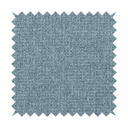 An upholstery fabric in a soft slate blue or dusty denim shade. The textile features a dense, multi-tonal basket weave with interlaced threads of sky blue, muted grey, and charcoal, creating a textured, linen-look surface with a matte finish.