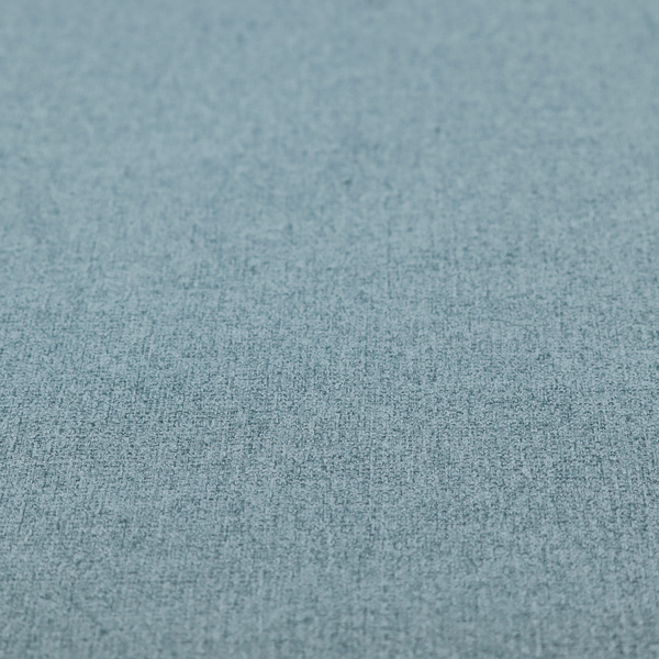 An upholstery fabric in a soft slate blue or dusty denim shade. The textile features a dense, multi-tonal basket weave with interlaced threads of sky blue, muted grey, and charcoal, creating a textured, linen-look surface with a matte finish.