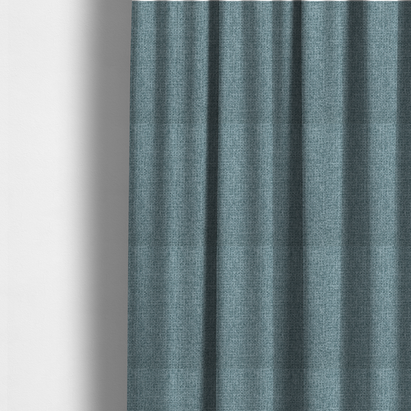 The fabric used to create these made-to-measure curtains is a upholstery fabric in a soft slate blue or dusty denim shade. The textile features a dense, multi-tonal basket weave with interlaced threads of sky blue, muted grey, and charcoal, creating a textured, linen-look surface with a matte finish.