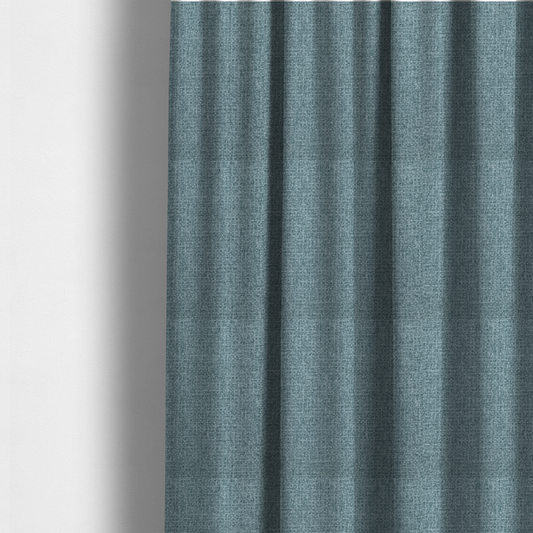 The fabric used to create these made-to-measure curtains is a upholstery fabric in a soft slate blue or dusty denim shade. The textile features a dense, multi-tonal basket weave with interlaced threads of sky blue, muted grey, and charcoal, creating a textured, linen-look surface with a matte finish.