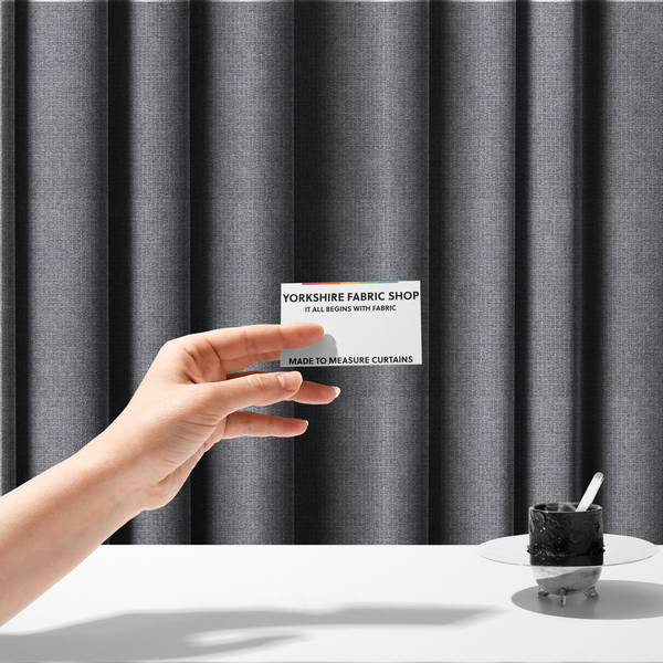 The fabric used to create these made-to-measure curtains is a upholstery fabric in a cool pebble grey. The interlacing of light grey and off-white threads creates a clean, contemporary basket weave pattern with a matte finish.