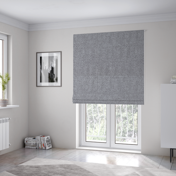 The fabric used to create these Roman blinds is a upholstery fabric in a cool pebble grey. The interlacing of light grey and off-white threads creates a clean, contemporary basket weave pattern with a matte finish.
