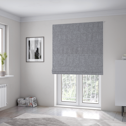 The fabric used to create these Roman blinds is a upholstery fabric in a cool pebble grey. The interlacing of light grey and off-white threads creates a clean, contemporary basket weave pattern with a matte finish.