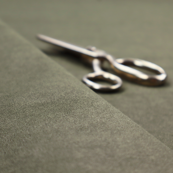 An olive-drab or sage-green fabric with a rich, distressed texture. The material features a dense, mottled pattern where dark earthy green fibres are interspersed with lighter, pale-green highlights. Like others in this series, it is characterized by faint, irregular light-coloured "crackle" lines that give it the appearance of weathered suede or industrial felt.